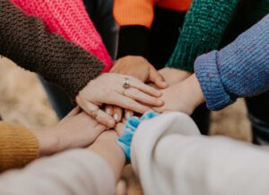 Viele Hände von Menschen einer Gruppe, die zusammen ein Ziel verfolgt