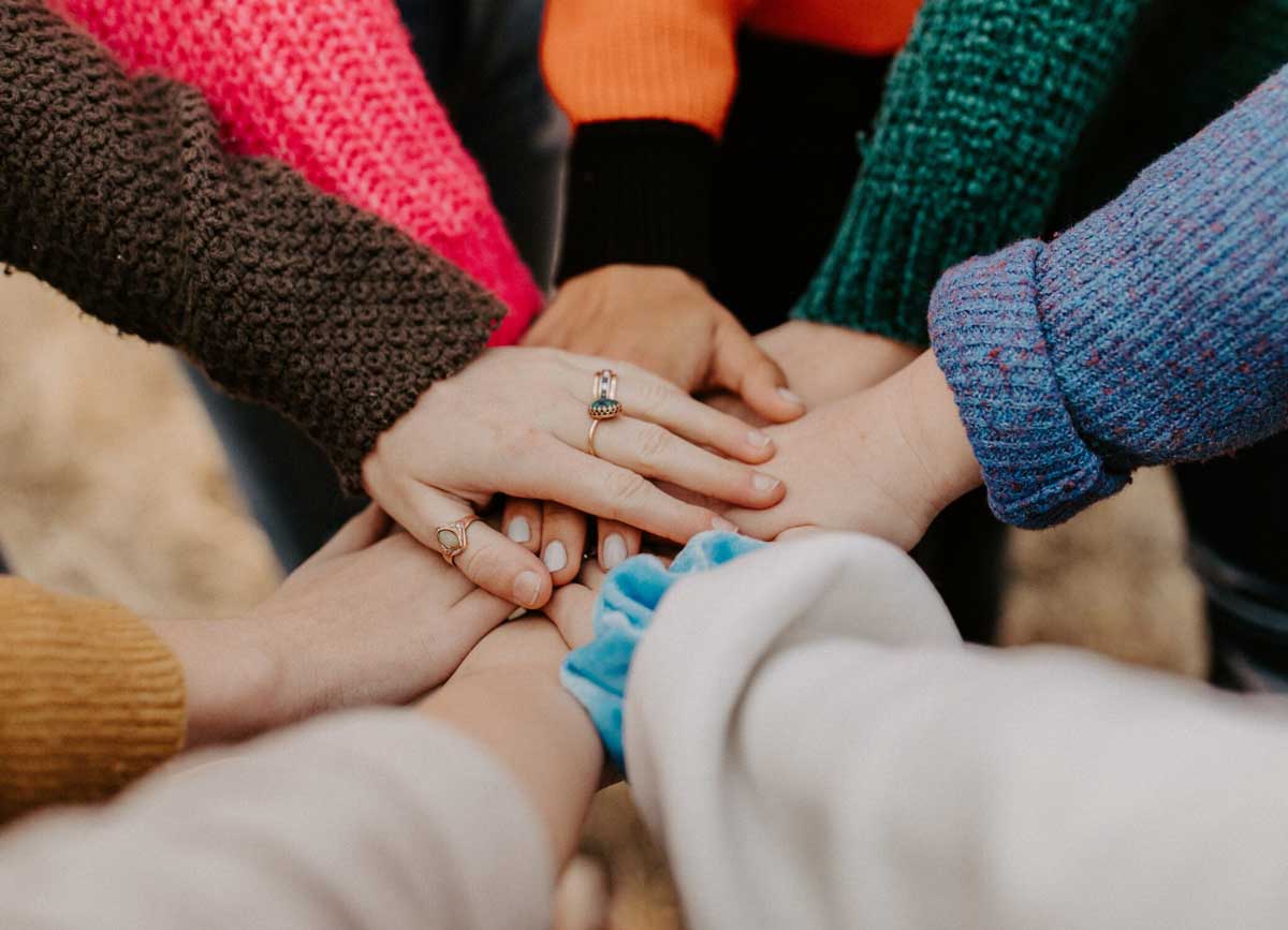 Viele Hände von Menschen einer Gruppe, die zusammen ein Ziel verfolgt
