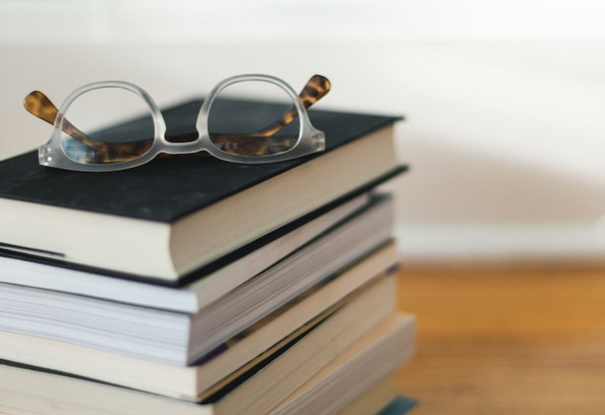 Eine Lesebrille liegt auf einem Bücherstapel