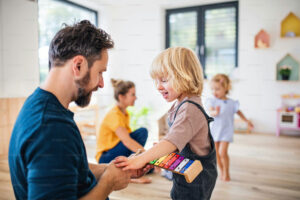 Ein Mann musiziert im Kindergarten mit einem Mädchen